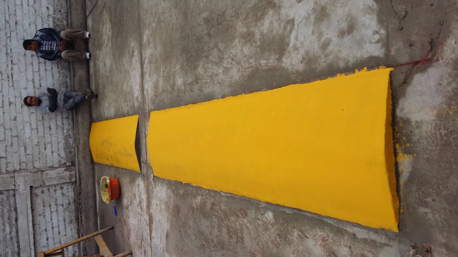 Rompe-muelle de concreto recién pintado de amarillo señalización en el muelle de carga de Tottus Pachacútec con dos operarios al fondo