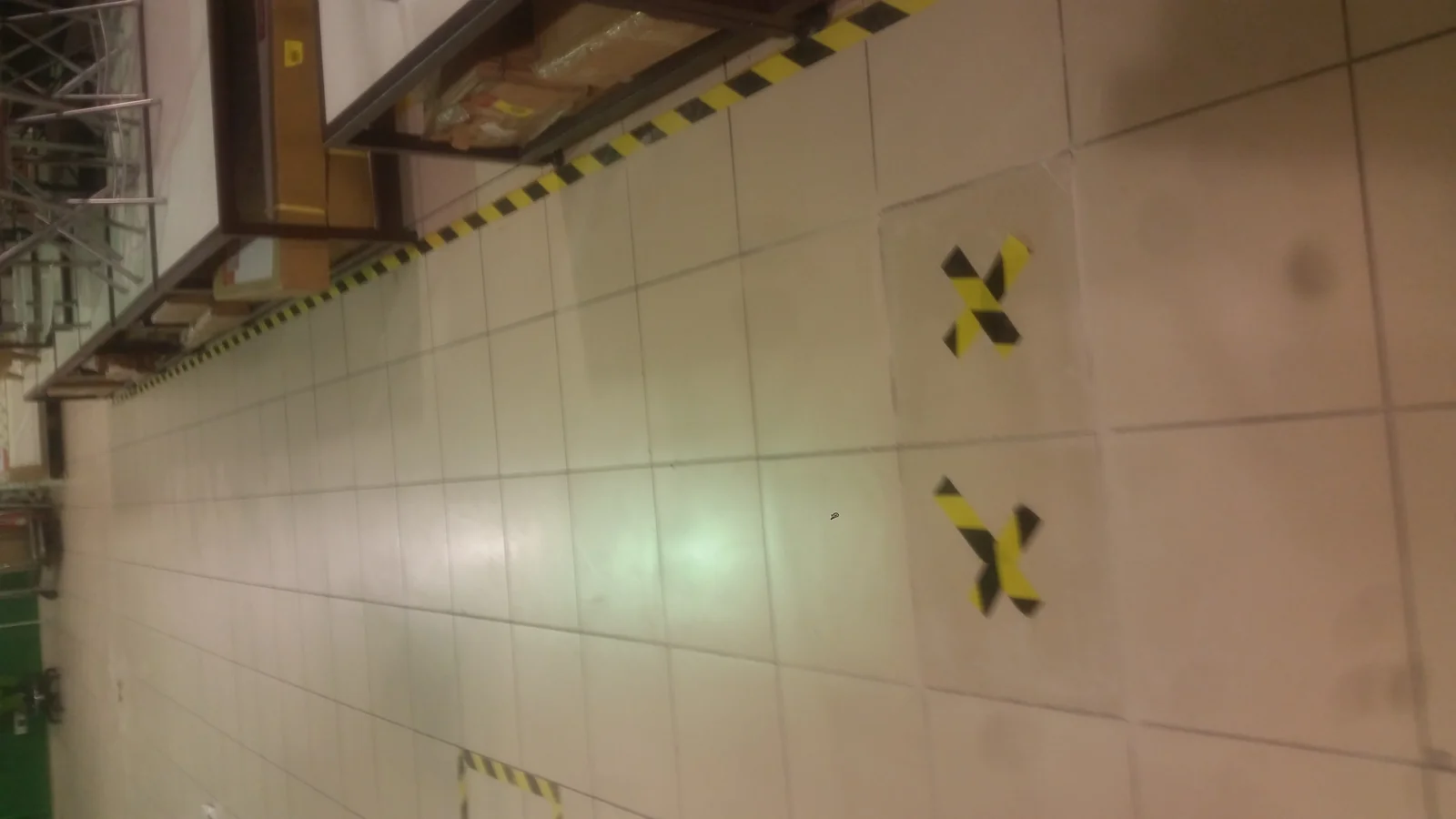 Piso de mayólica blanca con piezas marcadas con cinta de seguridad amarilla y negra frente al sector deli y comida al peso del Hipermercado Tottus Santa Anita