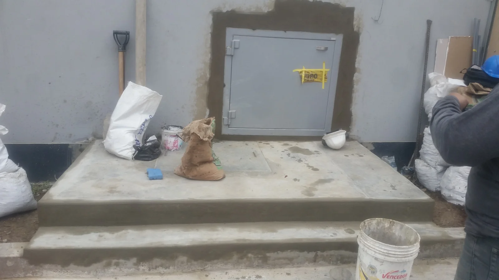 Plataforma de concreto con escalón terminada frente a puerta blindada de caja transfer en patio de servicio de Tottus El Agustino