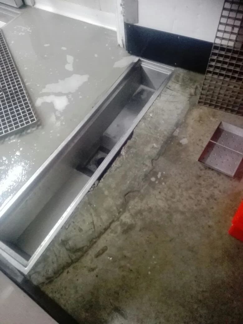 Canal de drenaje lineal de acero inoxidable abierto en piso de Tottus Mall del Sur mostrando salida al sumidero antes de instalar la reja